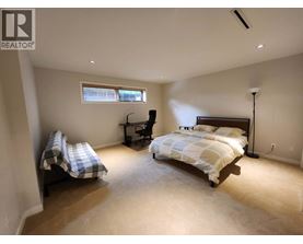 A bedroom with a bed, chair, and window.