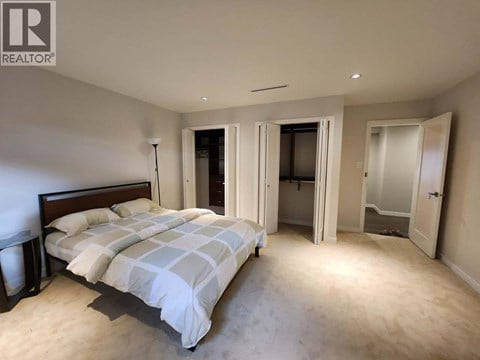 A bedroom with a large bed and a carpeted floor.