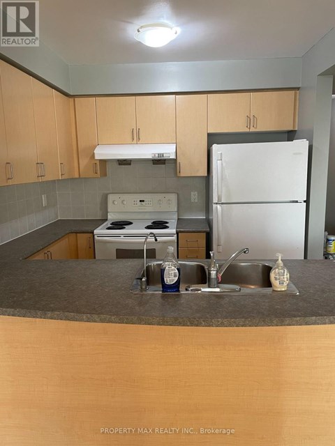 A kitchen with a white fridge, white stove and wooden cabinets.