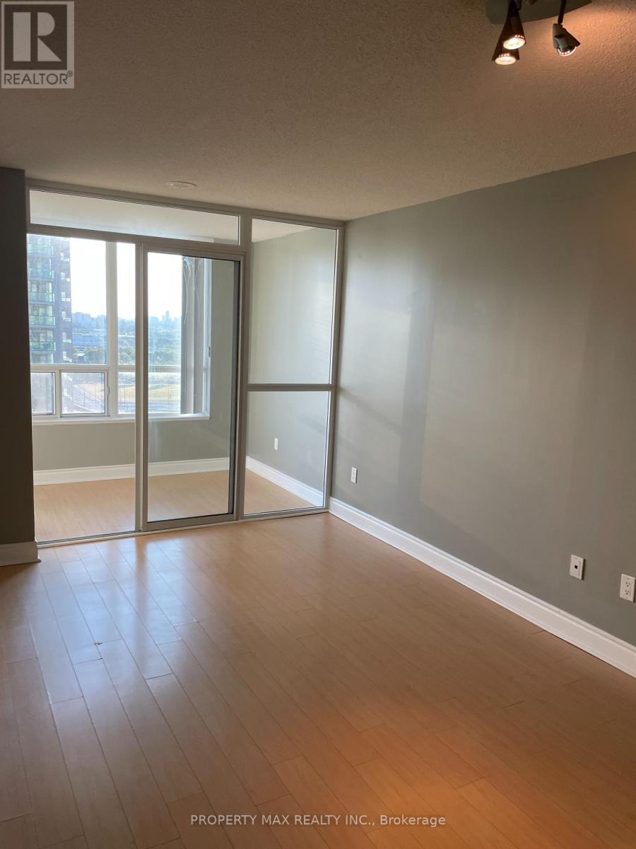 A room with wooden flooring and a large window with sliding glass doors.