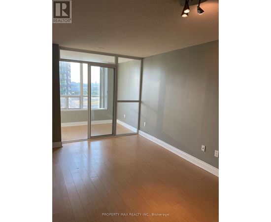 A room with wooden flooring and a large window with sliding glass doors.