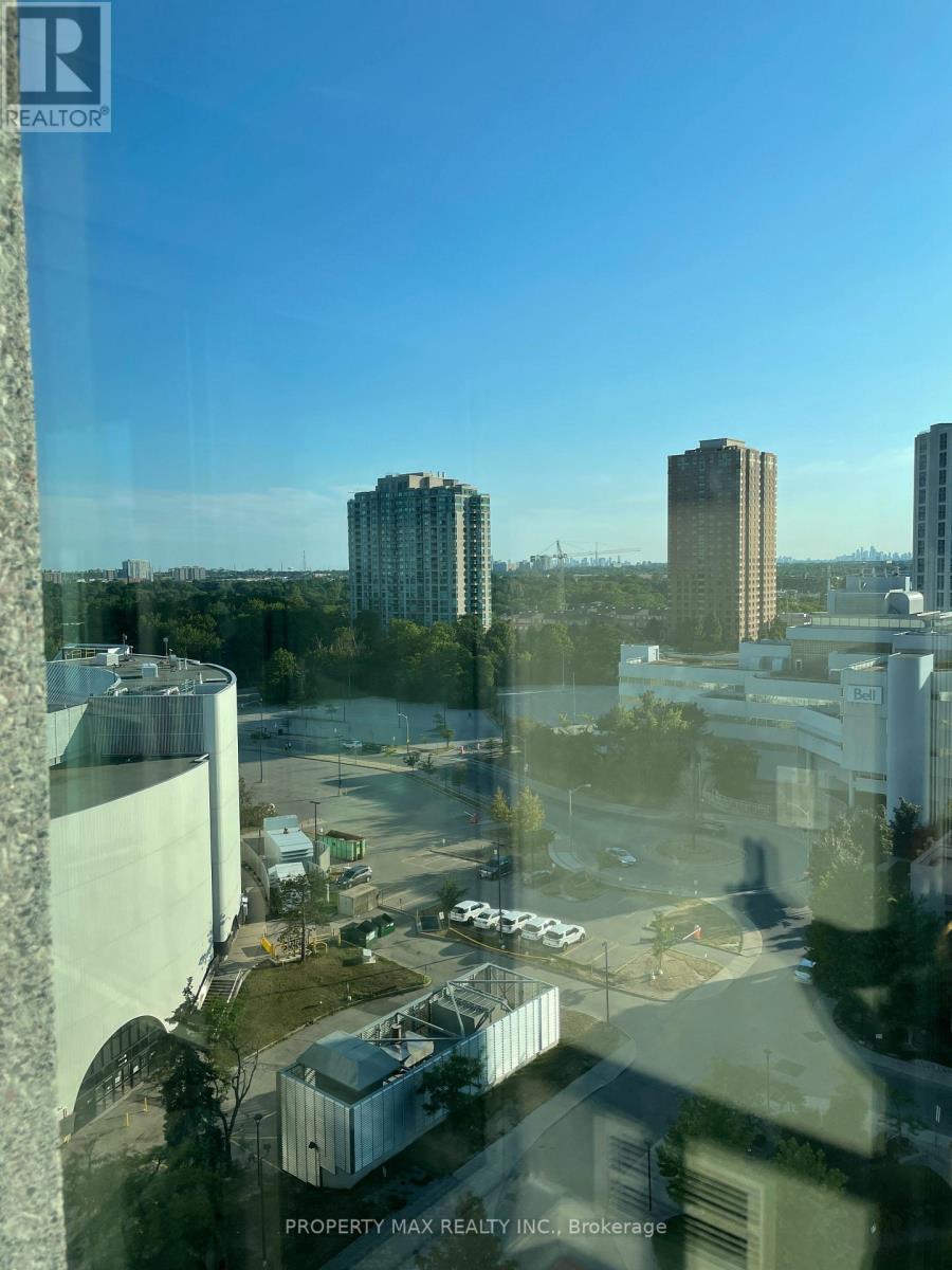 A view from a high-rise building looking out over a cityscape with buildings and a parking lot.