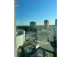 A view from a high-rise building looking out over a cityscape with buildings and a parking lot.