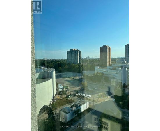 A view from a high-rise building looking out over a cityscape with buildings and a parking lot.