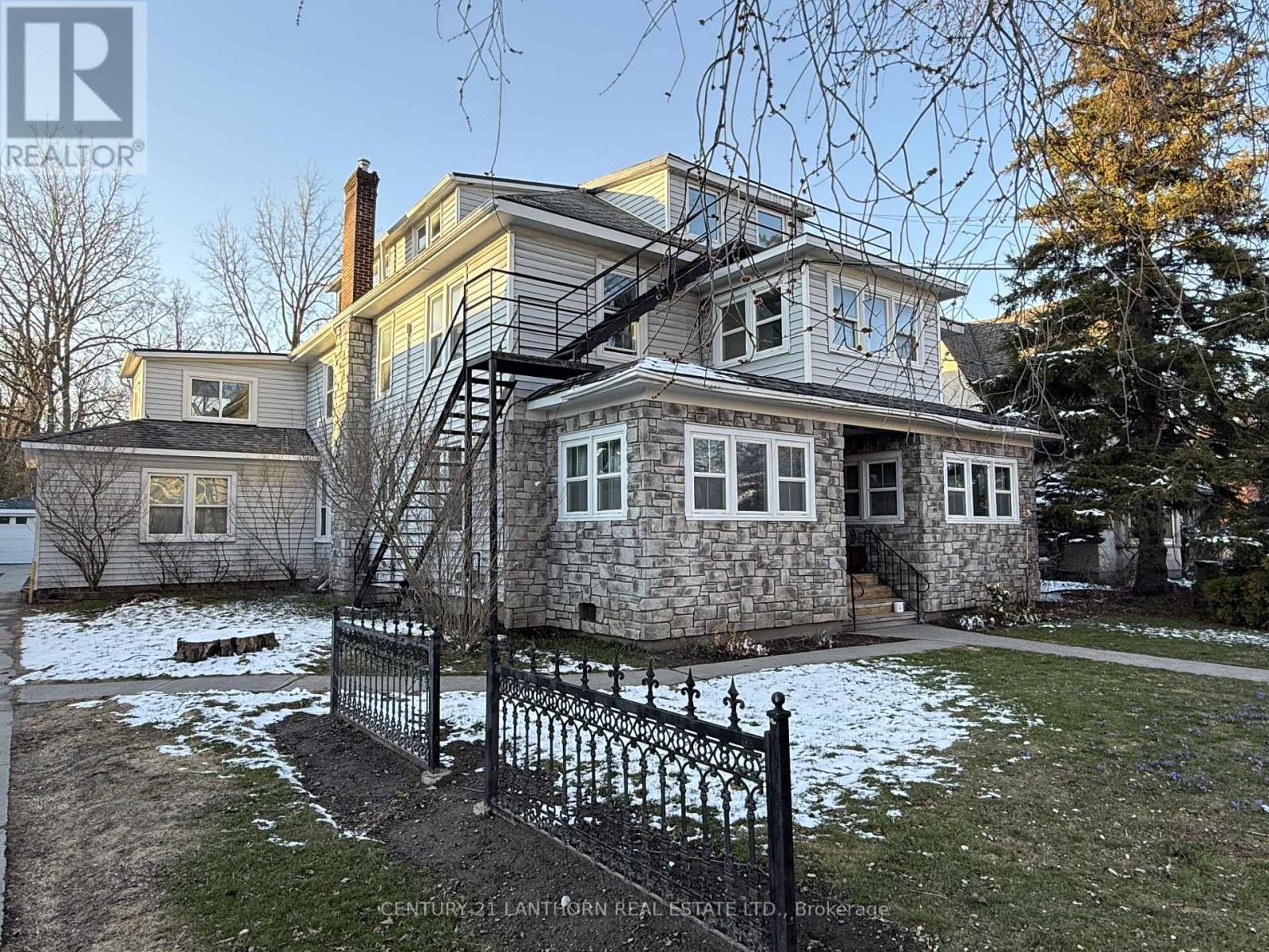 A house with a stone foundation and a black iron fence.