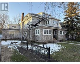 A house with a stone foundation and a black iron fence.