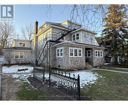 A house with a stone foundation and a black iron fence.