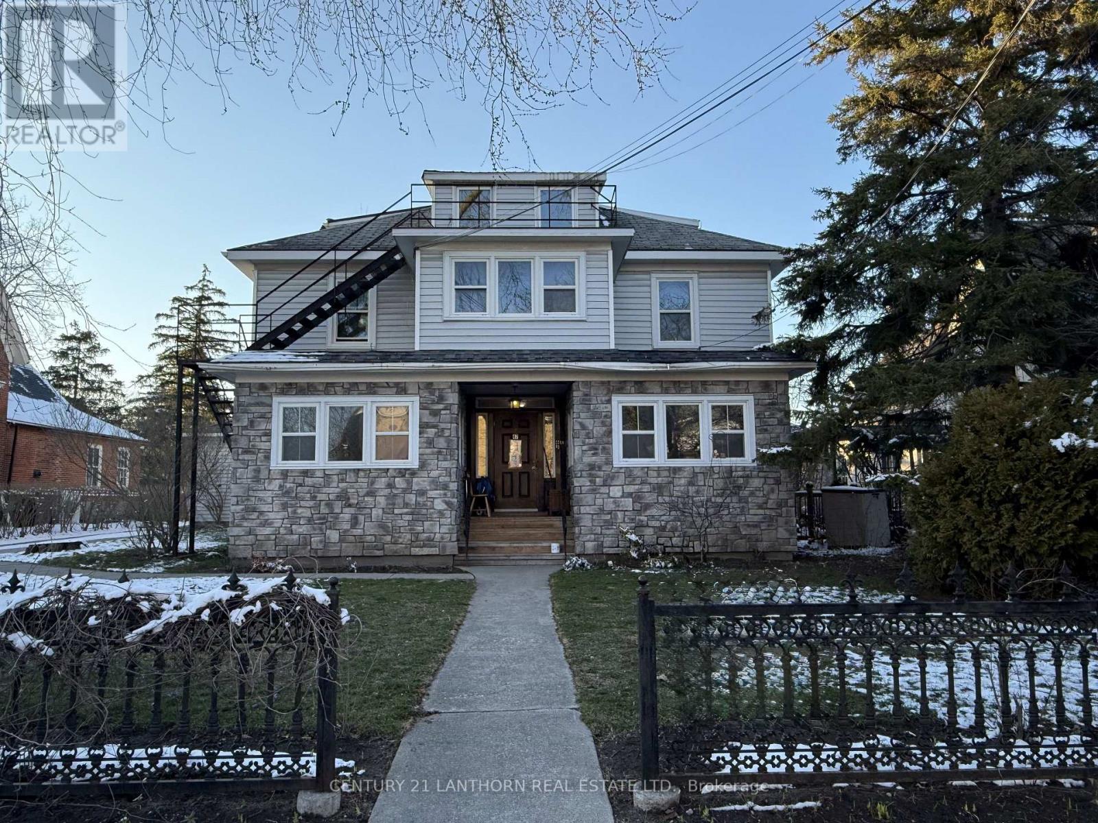 A house with a grey roof and a stone wall in front.