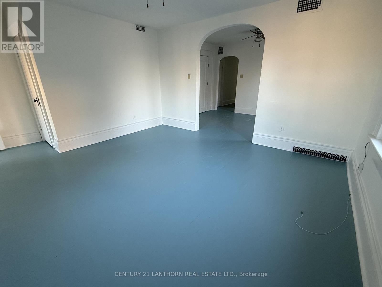 A spacious room with a white archway leading to another room.