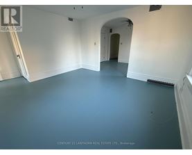 A spacious room with a white archway leading to another room.