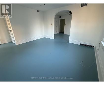 A spacious room with a white archway leading to another room.