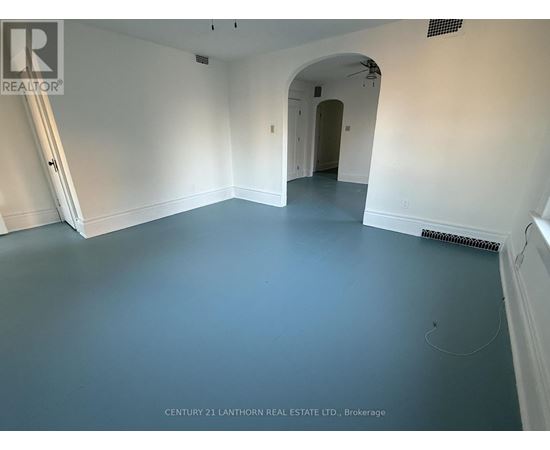 A spacious room with a white archway leading to another room.