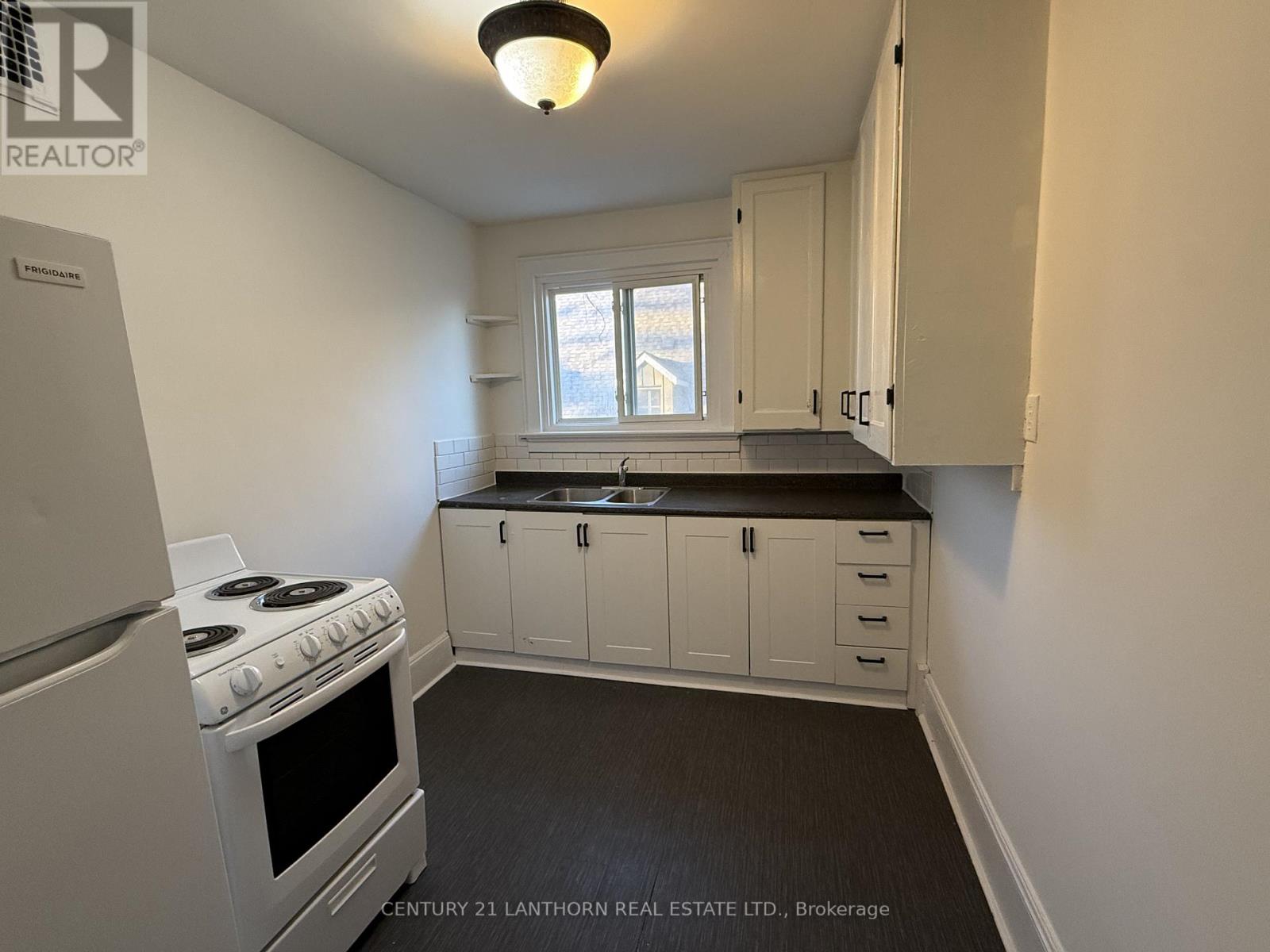 A kitchen with white cabinets and a stove top oven.