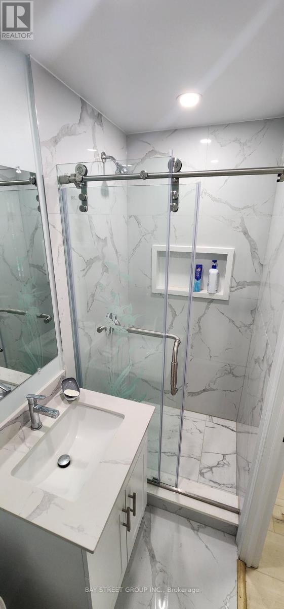 A bathroom with a marble wall and a walk-in shower.