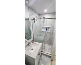 A bathroom with a marble wall and a walk-in shower.