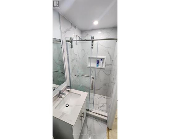 A bathroom with a marble wall and a walk-in shower.