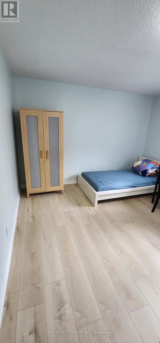 A bedroom with a bed, wooden floor, and a wardrobe.