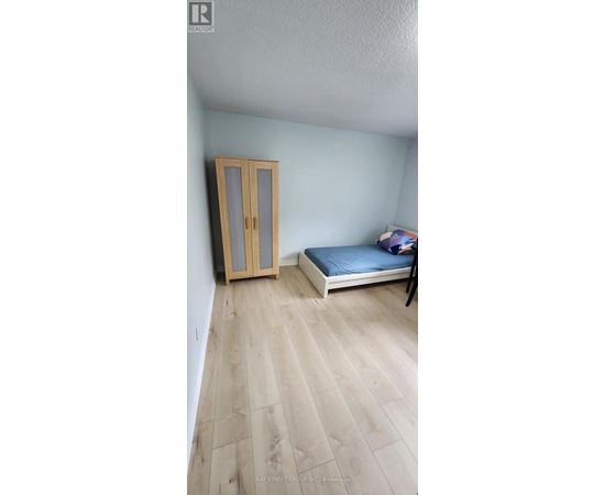 A bedroom with a bed, wooden floor, and a wardrobe.