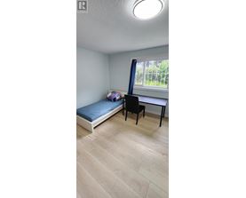 A room with a bed, desk, and chair.
