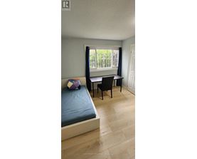 A bedroom with a bed, chair, and window.