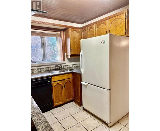 A white refrigerator in a kitchen with wooden cabinets.