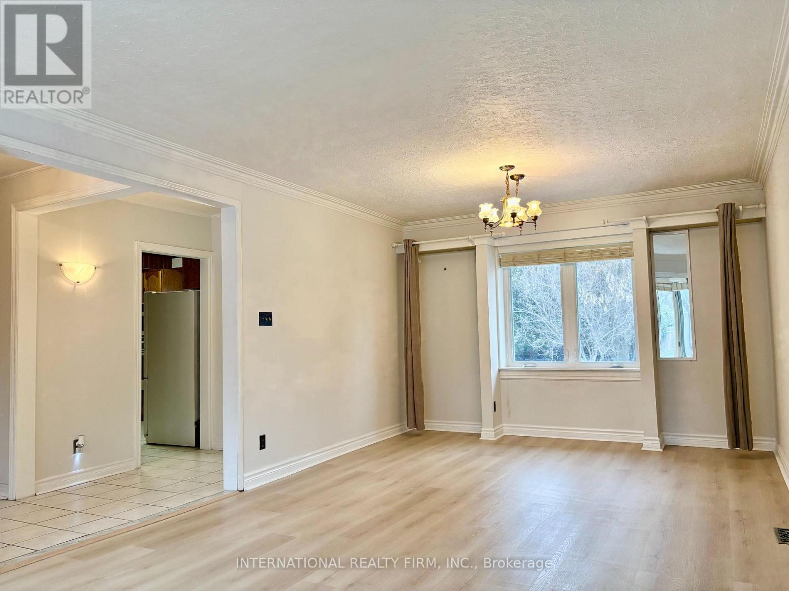 A spacious room with a chandelier and large windows.