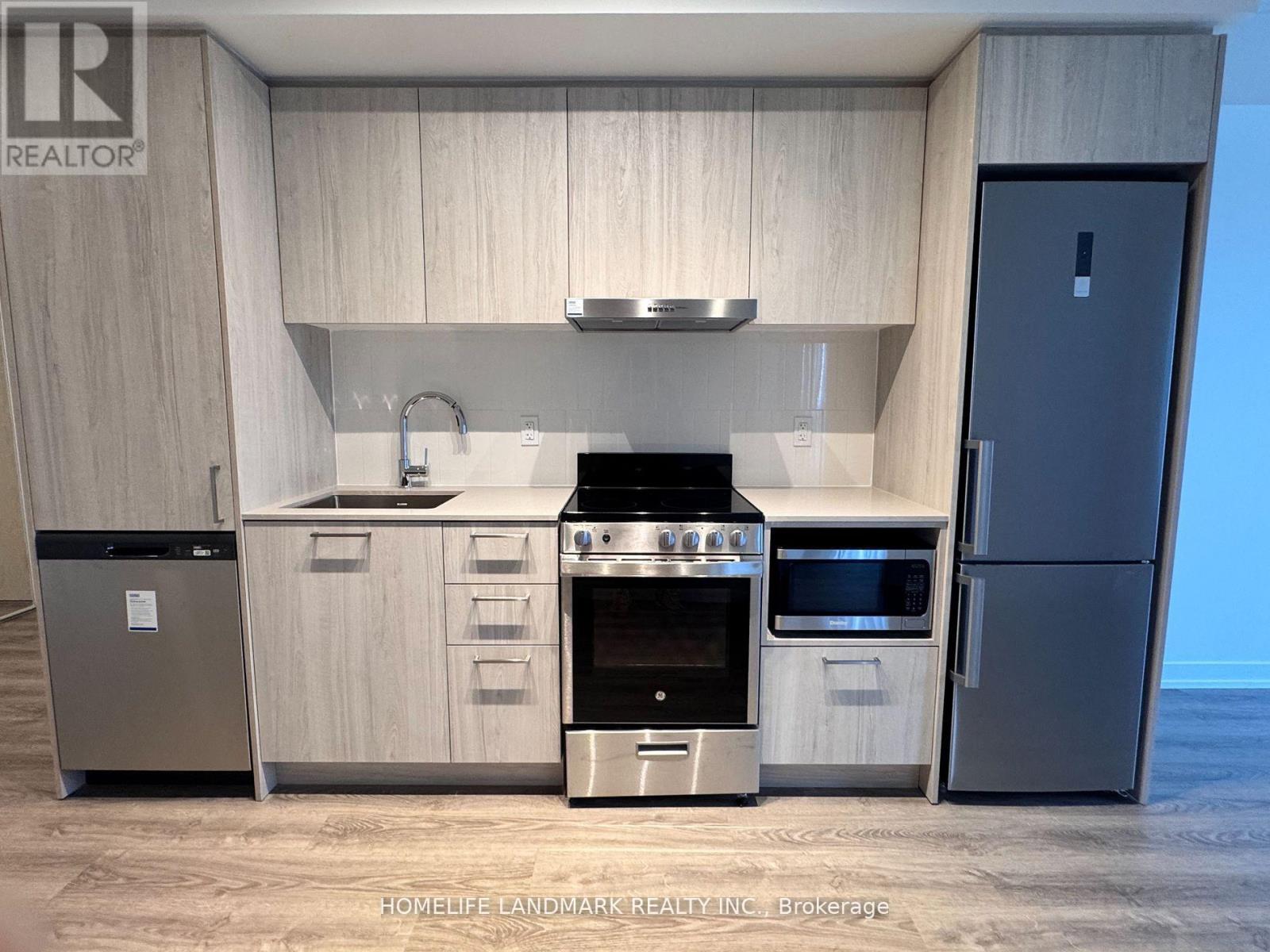 A modern kitchen with a stainless steel refrigerator and a stove top oven.