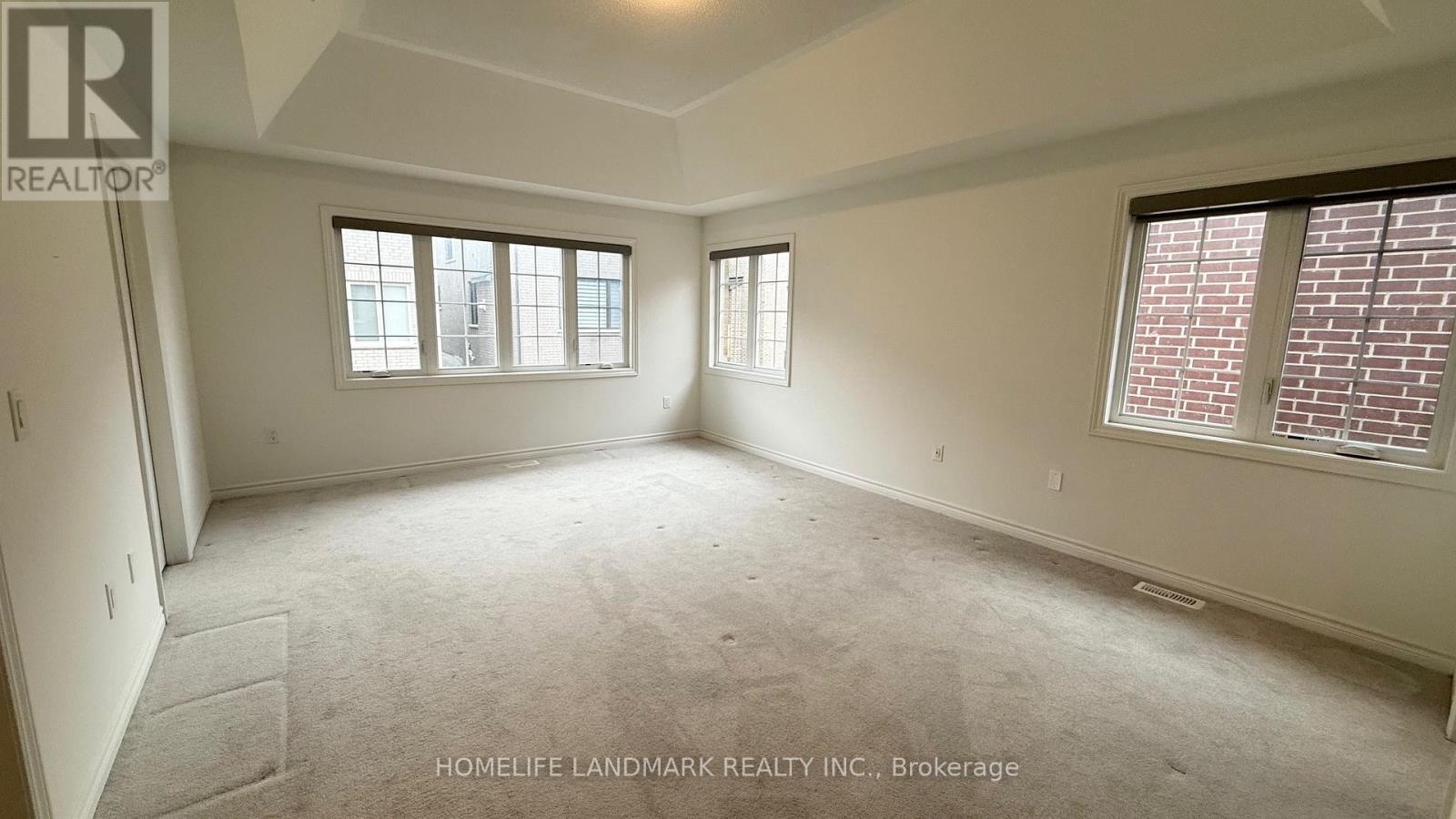 A spacious room with two windows and carpeted floor.