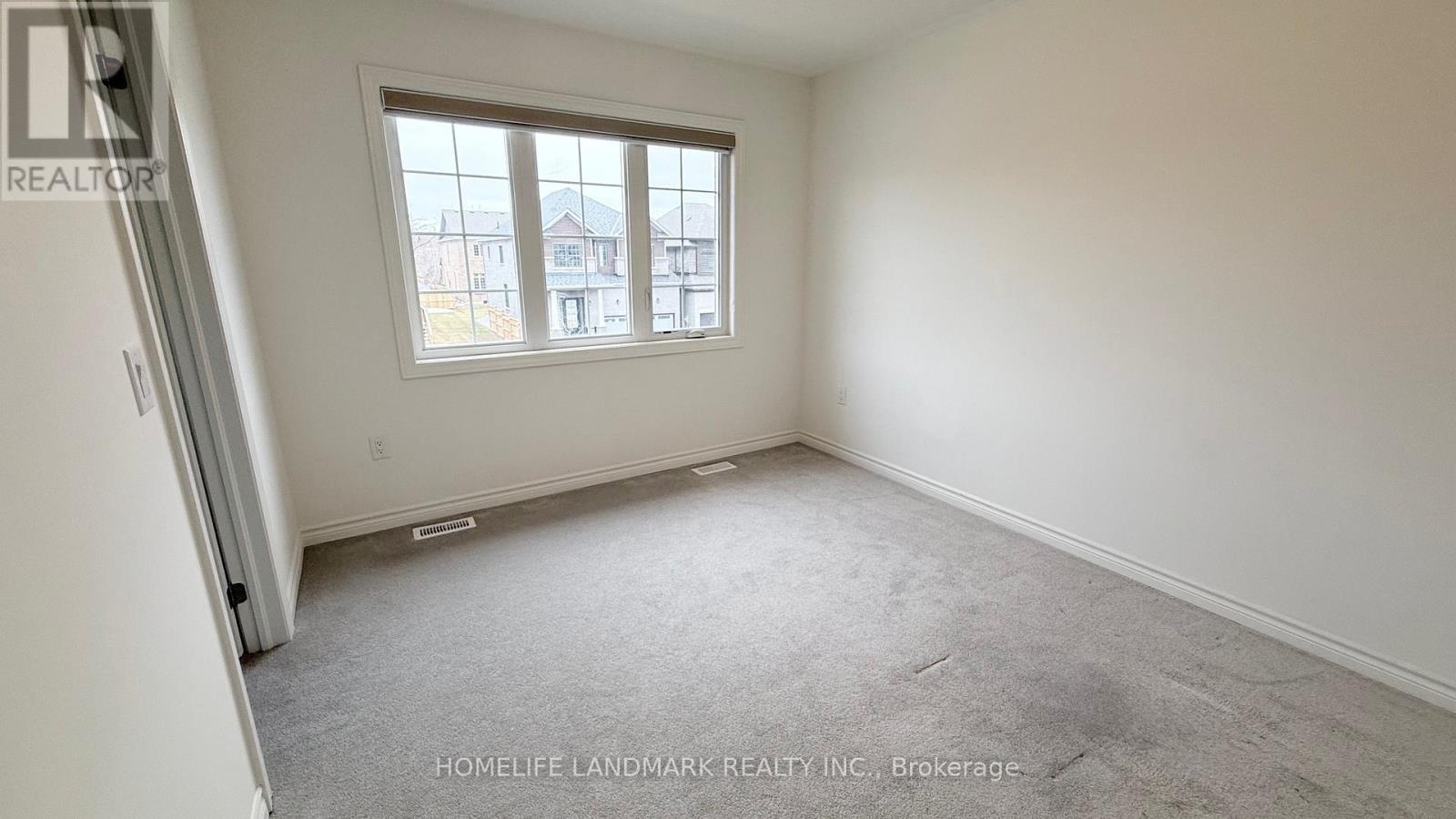 A room with a window showing a view of buildings outside.