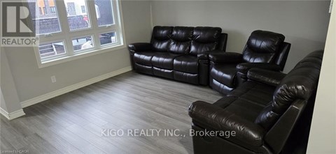 A living room with black leather furniture and a window.