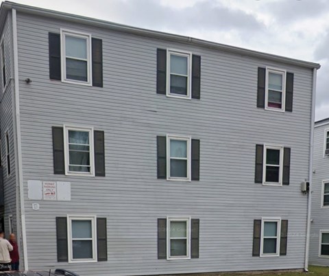 A grey building with a sign that says "For Rent".
