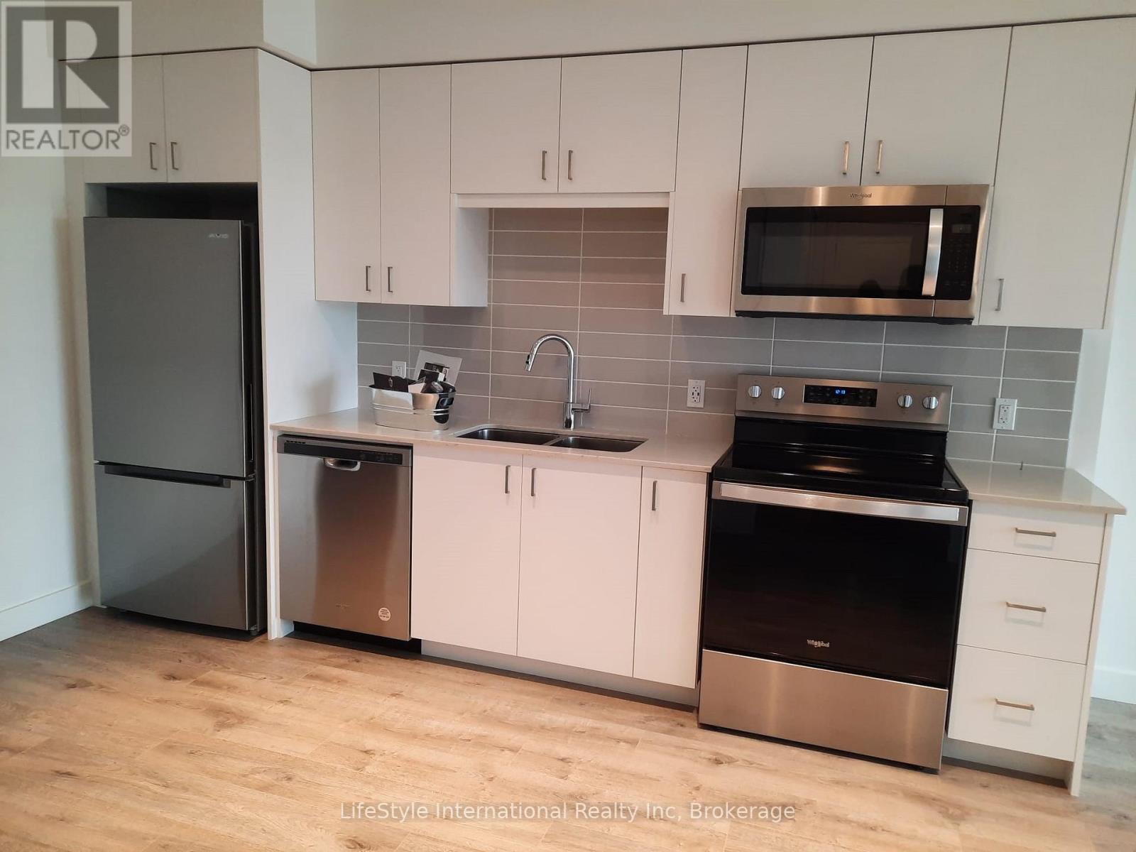 A kitchen with a black fridge, stainless steel dishwasher, and oven.