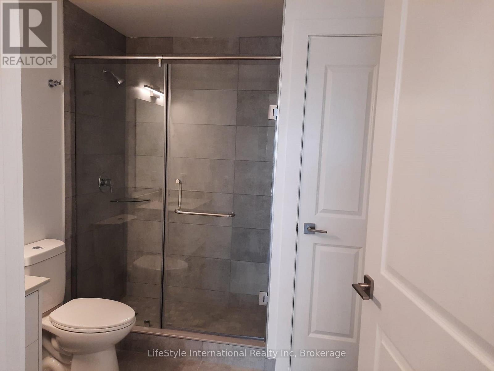 A white toilet sits next to a glass shower stall in a bathroom.