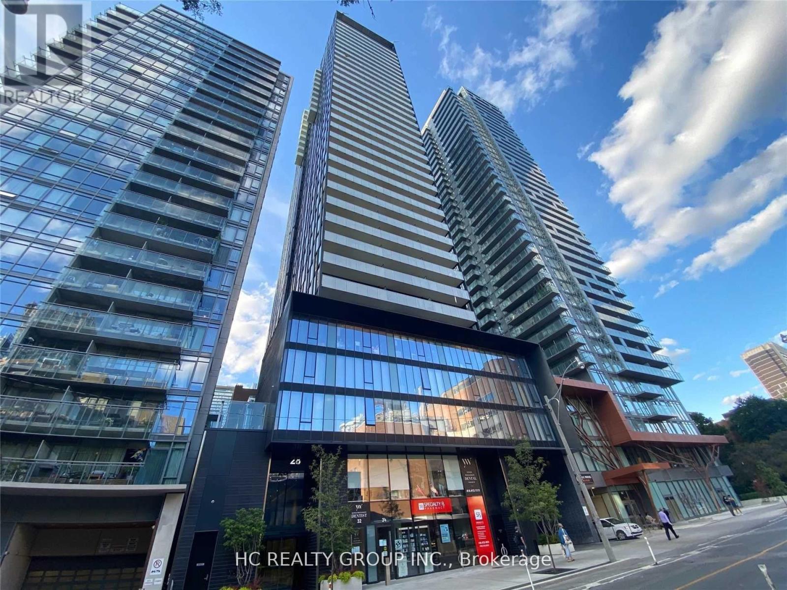 A modern building with glass windows and a sign that reads "HC REALTY GROUP INC. Brokerage".