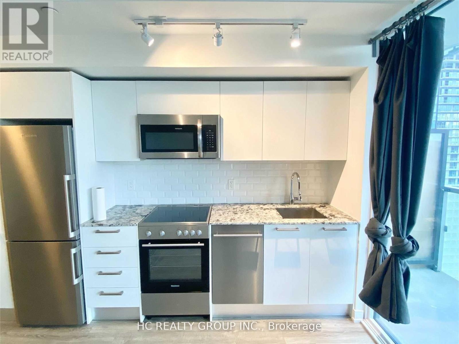 A modern kitchen with stainless steel appliances and white cabinets.