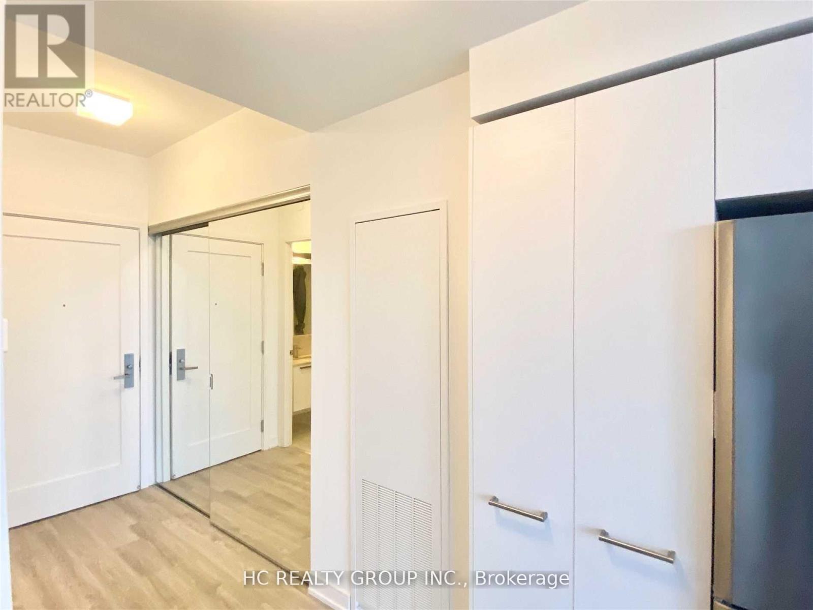 A kitchen with white cabinets and a refrigerator.