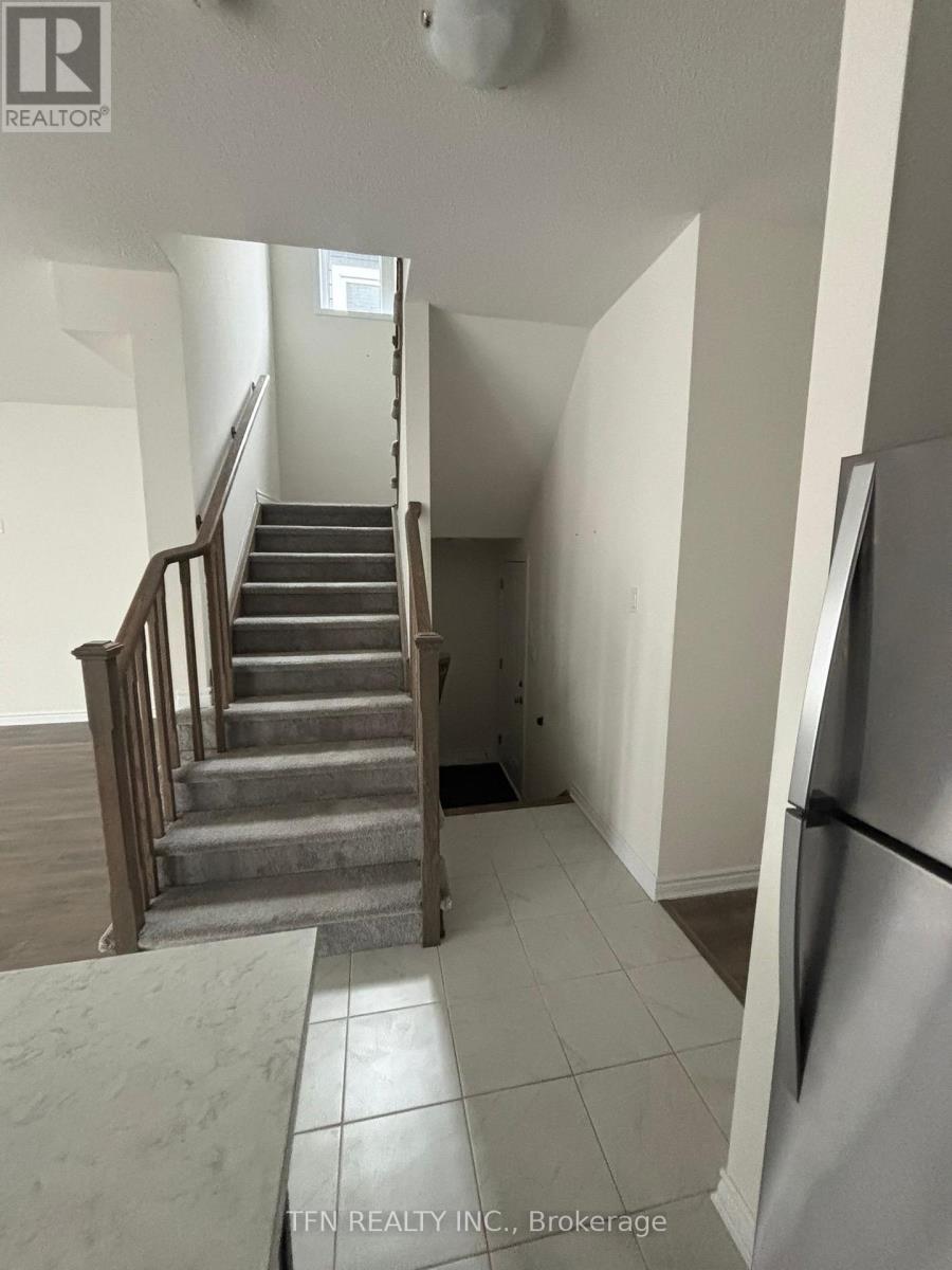 A staircase in a house with a refrigerator on the side.