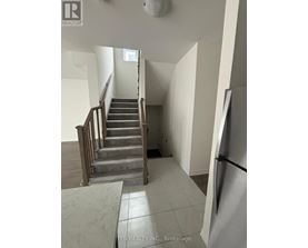 A staircase in a house with a refrigerator on the side.