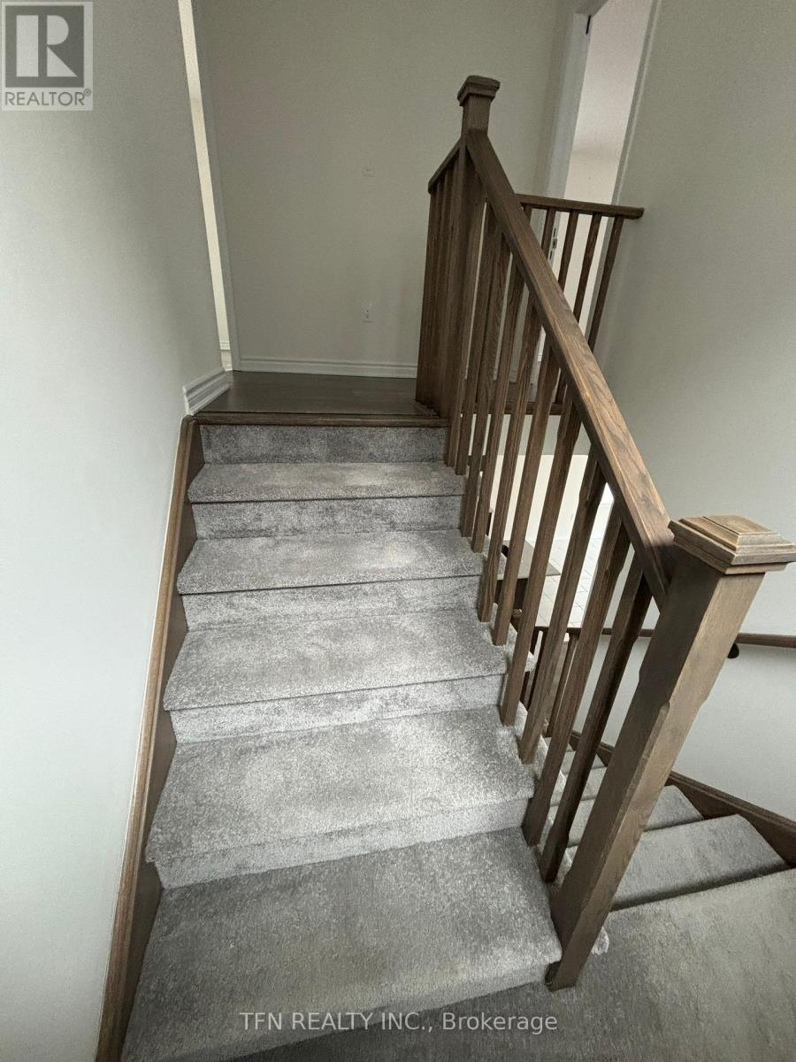 A staircase with a wooden railing and grey carpeted steps.