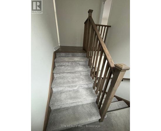 A staircase with a wooden railing and grey carpeted steps.