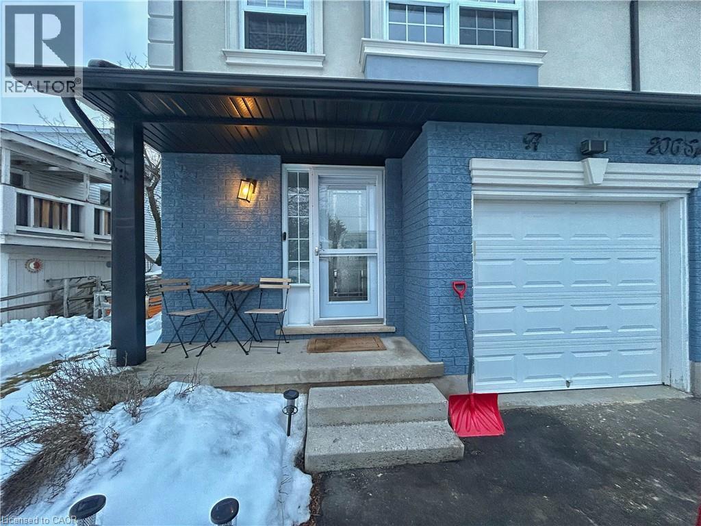 A blue house with a white garage door and a red flag on the ground.