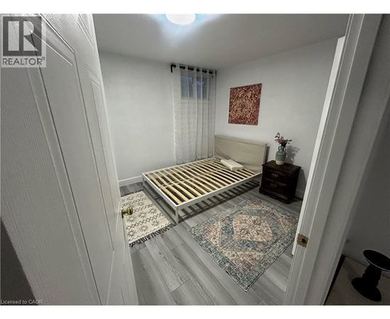 A bedroom with a bed, a rug, and a picture on the wall.