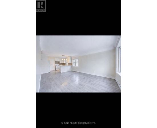 A spacious room with a kitchen area in the background.