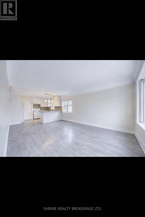 A spacious room with a kitchen area in the background.