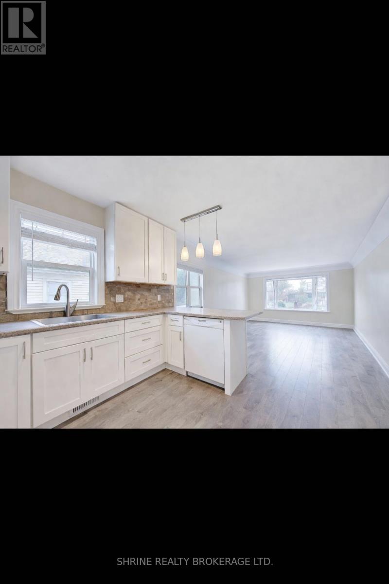 A well-lit kitchen with wooden floors and white cabinets.