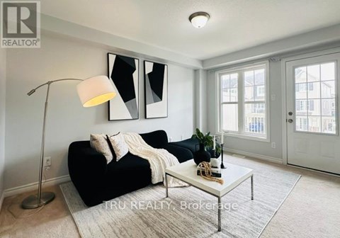 A well-lit living room with a black sofa and a white floor lamp.