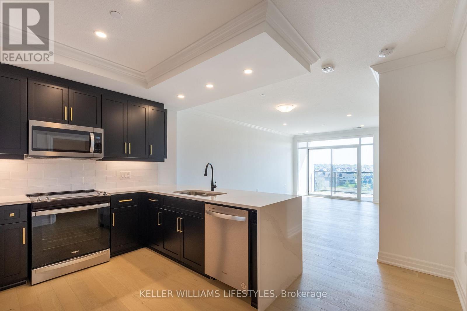 A modern kitchen with black cabinets and stainless steel appliances.