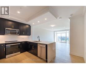 A modern kitchen with black cabinets and stainless steel appliances.