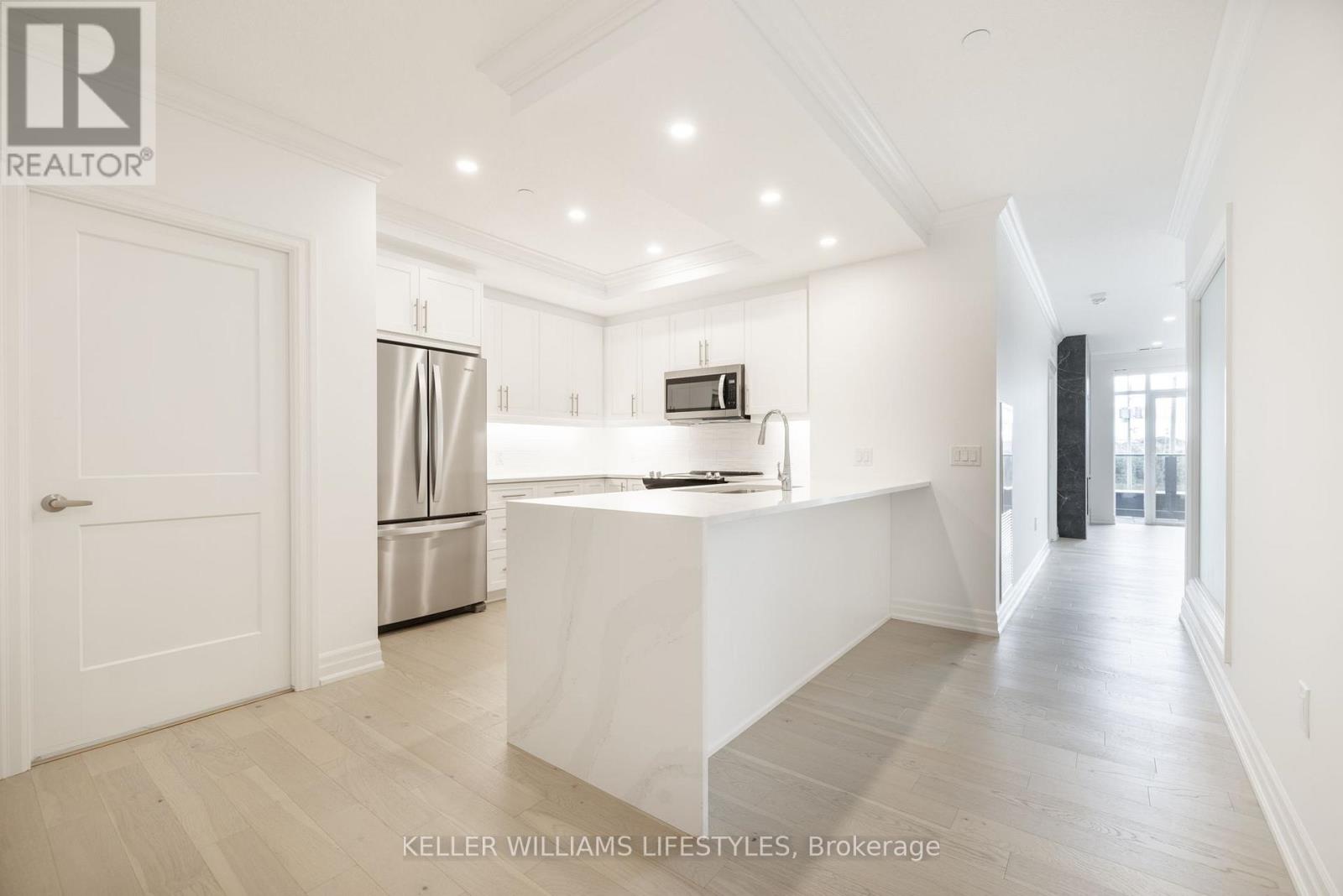 A spacious kitchen with white cabinets and a refrigerator.