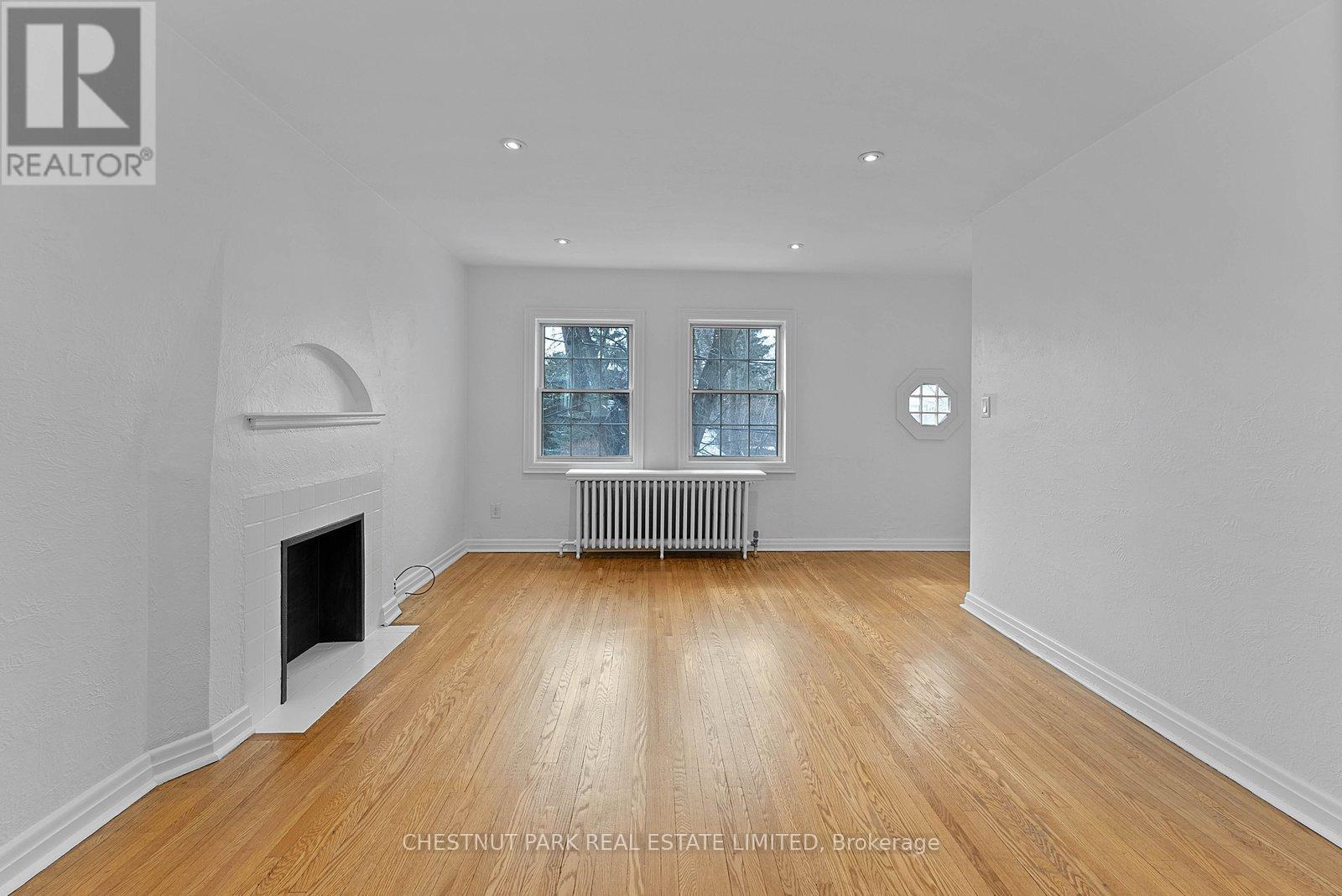A spacious room with a fireplace and wooden flooring.